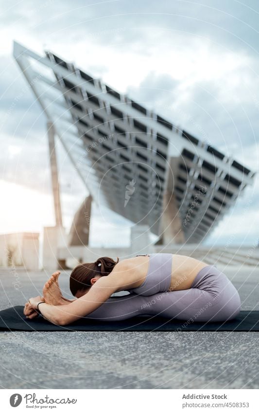 Frau macht sitzende vorwärts falten asana auf der Straße Yoga Asana weitergeben Pferch solar Panel Übung Training üben Energie beweglich Dame modern