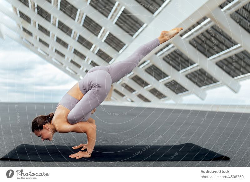 Flexible Frau beim Flying Lizard Asana Fliegende Eidechse Yoga solar Panel Übung Training Straße Gleichgewicht üben Energie beweglich modern Sportbekleidung
