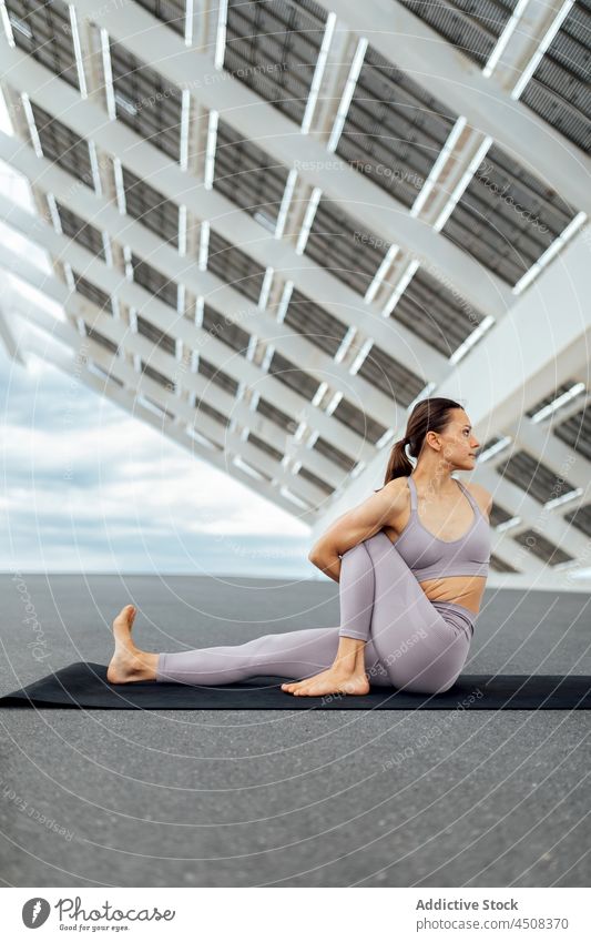 Frau macht gedrehte Salbei Marichis Asana auf der Straße gedrehte Salbei-Marichis Yoga solar Panel Übung Training üben Energie beweglich Dame modern