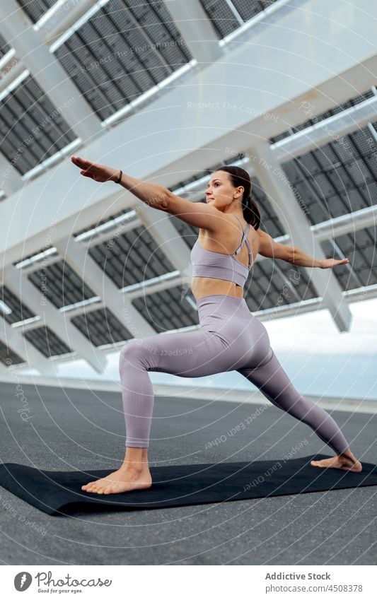 Frau macht Krieger Asana auf der Straße Yoga solar Panel Übung Training üben Energie beweglich Dame modern Gleichgewicht Sportbekleidung Wellness Achtsamkeit