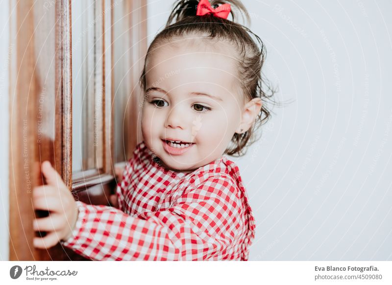 close up Porträt der schönen Baby-Mädchen zu Hause suchen durch Fenster Tür. Ein Jahr altes Mädchen. Lifestyles innen Kaukasier heimwärts Blick Warten traumhaft