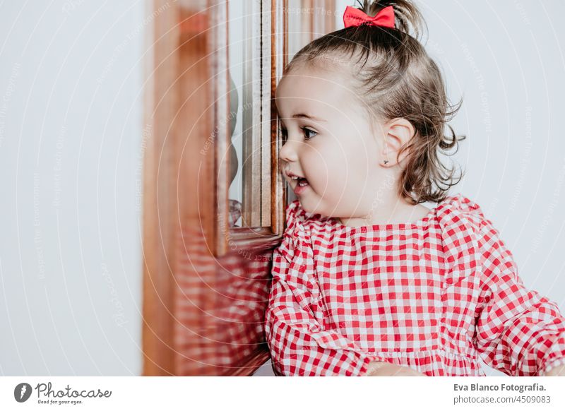close up Porträt der schönen Baby-Mädchen zu Hause suchen durch Fenster Tür. Ein Jahr altes Mädchen. Lifestyles innen Kaukasier heimwärts Blick Warten traumhaft