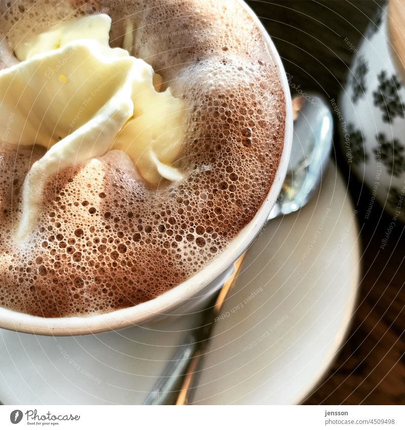Eine Tasse heiße Schokolade mit Sahne Detailaufnahme Kakao Heiße Schokolade Genuss Café Schaum sahnehäubchen Heißgetränk lecker süß Becher Löffel