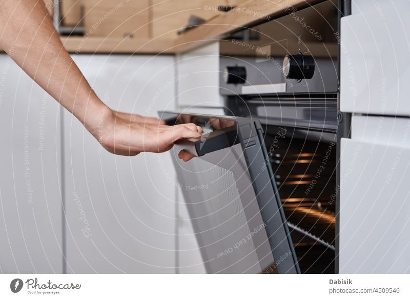Frau öffnet Tür des Elektrobackofens Ofen Küche offen Geräte Lebensmittel elektrisch modern Haushalt Hand backen Kuchen selbstgemacht Erwachsener Vorrichtung