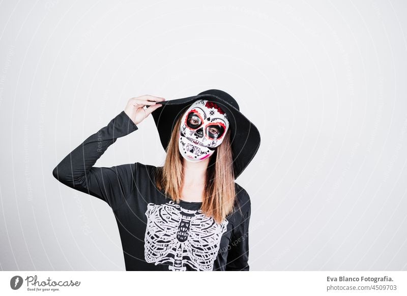 Frau trägt mexikanische Gesichtsmaske während Halloween-Feier. Skelett-Kostüm und schwarzen stilvollen Hut. Halloween Party Konzept traditionell Blume Tod