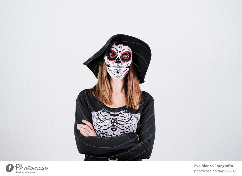Frau trägt mexikanische Gesichtsmaske während Halloween-Feier. Skelett-Kostüm und schwarzen stilvollen Hut. Frau mit verschränkten Armen. Halloween-Party-Konzept