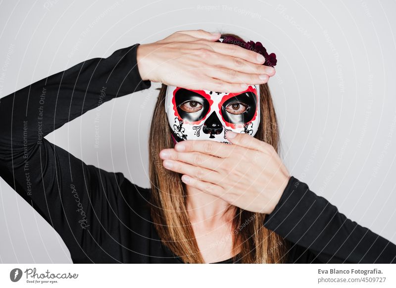 Frau trägt mexikanische Gesichtsmaske während Halloween-Feier. Frau trägt Skelett-Kostüm und rote Rosen Diadem auf dem Kopf. Halloween-Party-Konzept