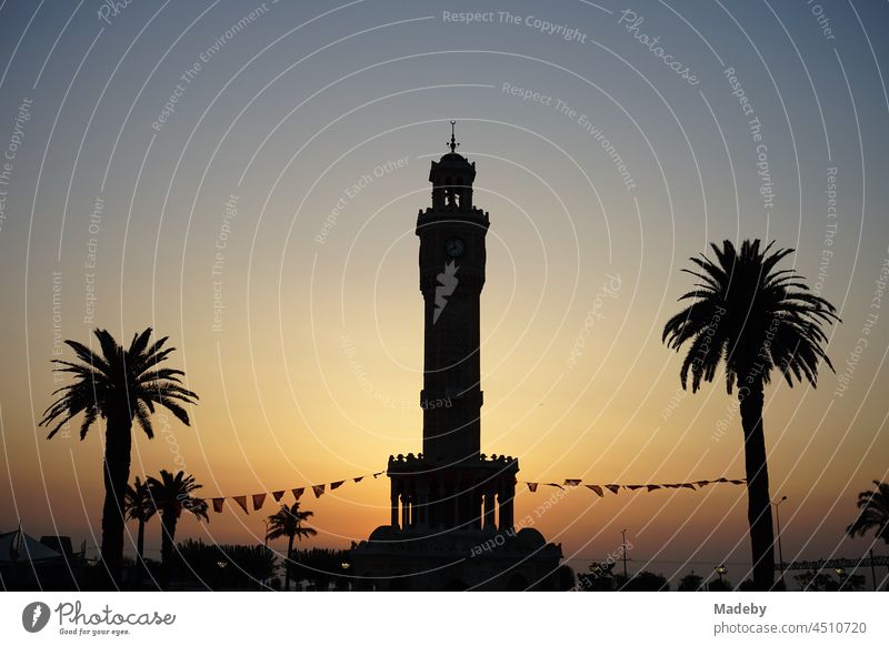 Der Uhrturm von Izmir mit mediterranen Palmen im Licht der untergehenden Sonne am Konak Platz im alten Smyrna am Ägäischen Meer in der Türkei Sonnenuntergang