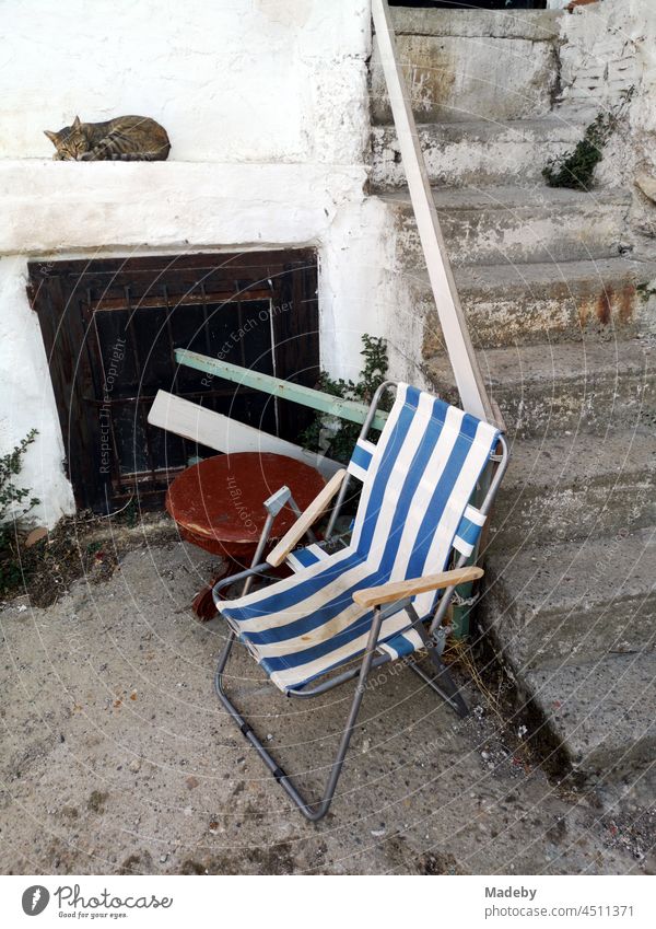 Gestreifter Campingstuhl im Hof neben einem Treppenaufgang mit schlafender Katze in der Altstadt von Foca am Ägäischen Meer bei Izmir in der Türkei Stuhl