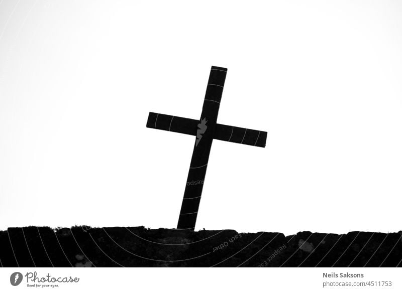 Gekrümmtes katholisches christliches Kreuz Silhouette auf Friedhofszaun. Schwarz und weiß abstrakt Kunst Hintergrund Glaube schwarz Katholizismus Christus