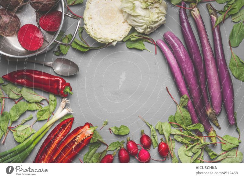Gemüse Lebensmittel Hintergrund mit Paprika, Aubergine, Rettich, Rote Beete, Kohl und Frühlingszwiebeln auf grauen Küchentisch. Saisonales Gemüse. Rahmen mit Kopierbereich. Ansicht von oben.