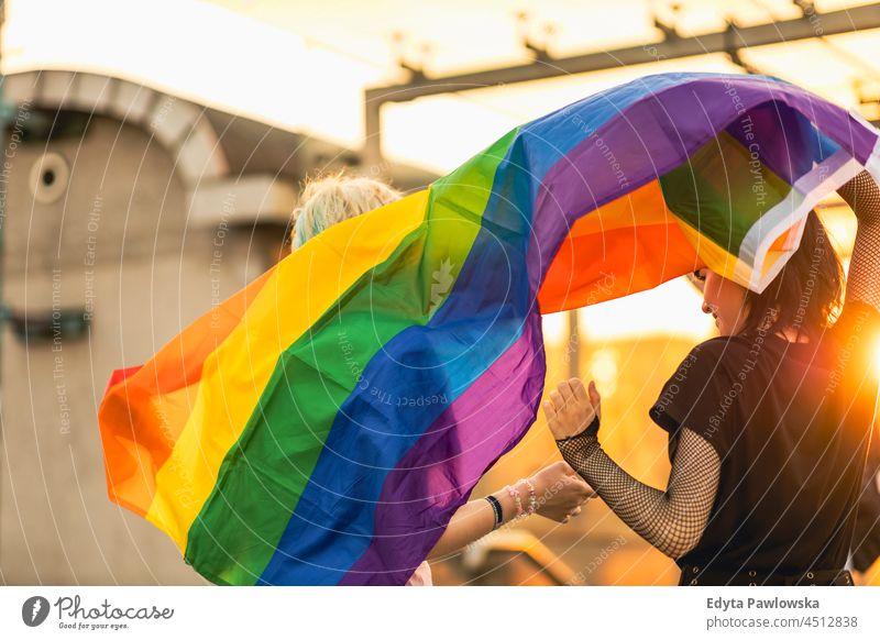 Glückliches junges Paar winkt mit Regenbogenflagge Homosexuelles Paar Liebe Zusammensein romantisch queer nicht-binär geschlechtsfluid lgbt Gleichstellung