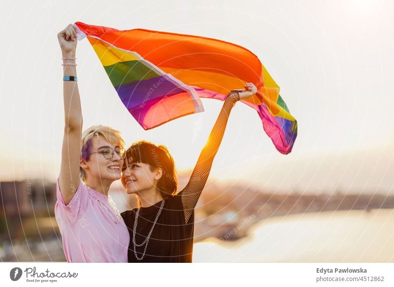 Glückliches nicht-binäres Paar winkt mit Regenbogenflagge Homosexuelles Paar Liebe Zusammensein romantisch queer geschlechtsfluid lgbt Gleichstellung