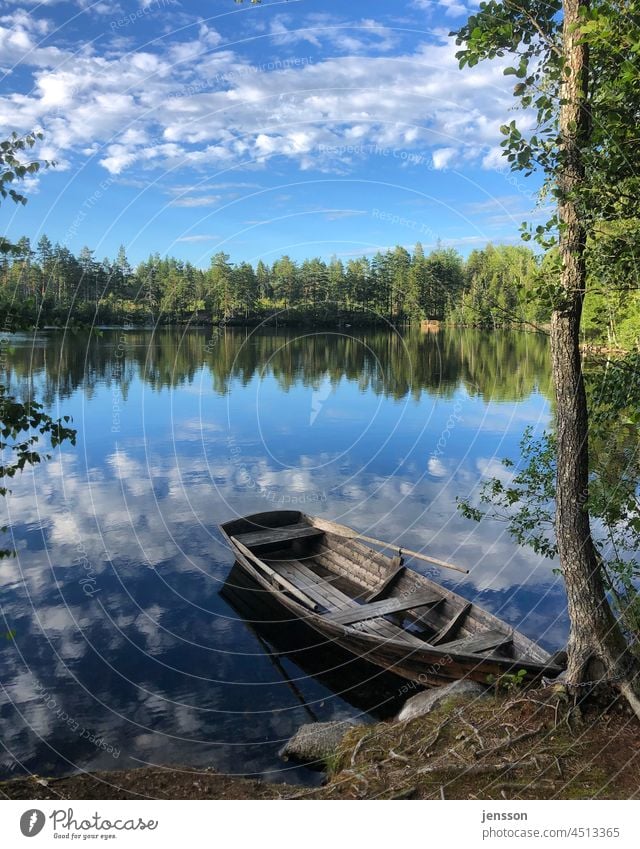 Ruderboot an einem See in Schweden Skandinavien Sommer Seeufer Sommerurlaub sommerlich Blauer Himmel blauer Himmel mit Wolken Spiegelung im Wasser Bootsfahrt