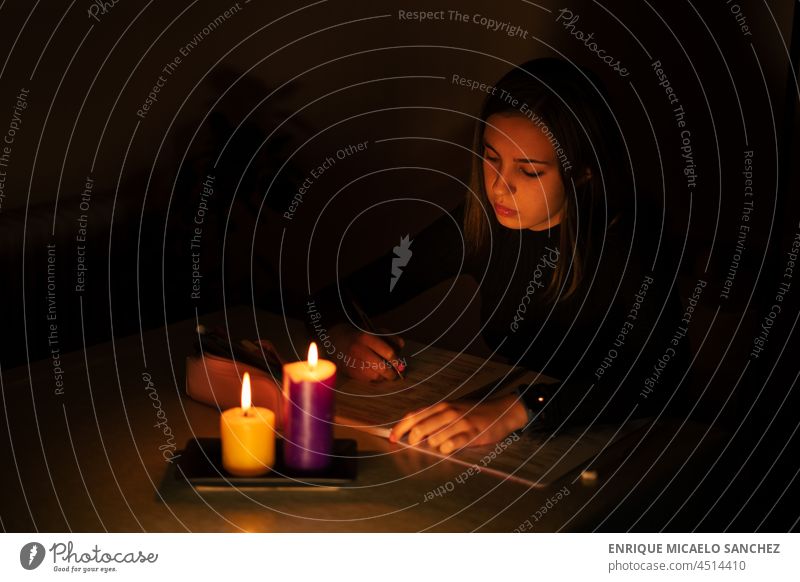 Junge Frau studiert bei Kerzenlicht. Blackout Konzept, Stromausfall Feuer Flamme Brandwunde Dunkelheit glühen glühend Hoffnung Gedenkstätte Frieden brennend
