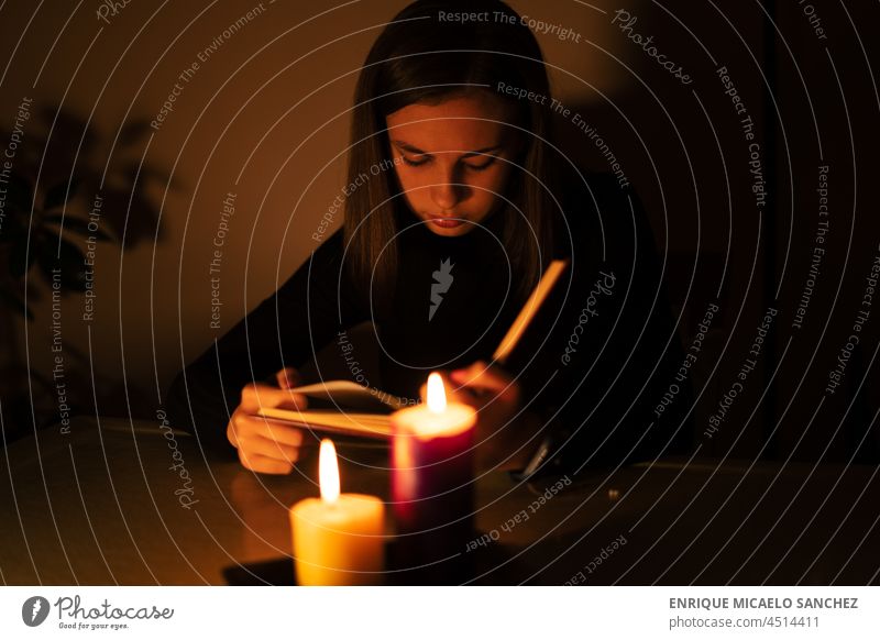 Junge Frau liest bei Kerzenlicht. Blackout Konzept, Stromausfall Feuer Flamme Brandwunde Dunkelheit glühen glühend Hoffnung Gedenkstätte Frieden brennend Nacht