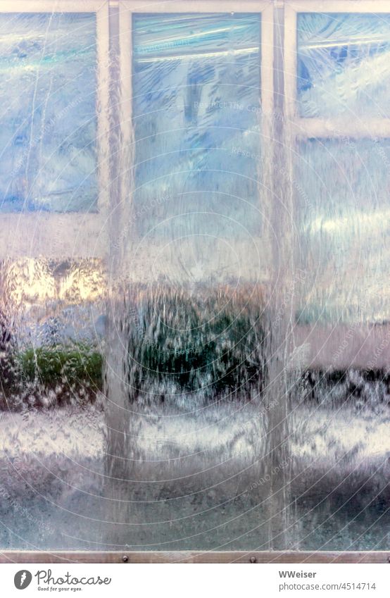 Abstraktes Bild von Wasser, das über eine durchsichtige Plastik- oder Glasfläche läuft, im Hintergrund sieht man Schemen einer Kleinstadt Wasserfall stürzen