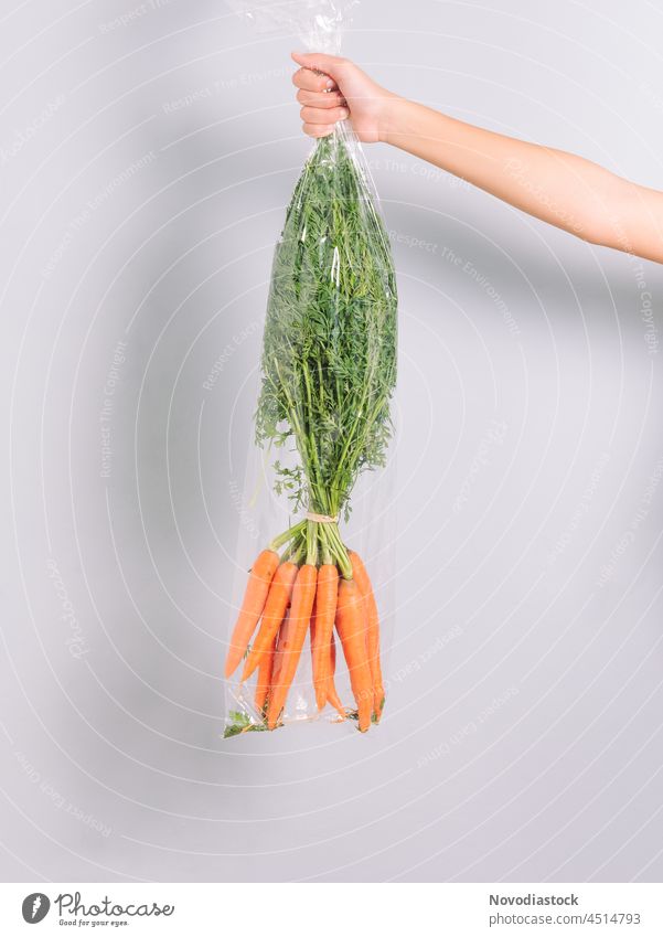 Hand hält eine Plastiktüte mit Karotten Bestandteil Diät Lebensmittel farbenfroh vereinzelt Salatbeilage Ernährung lecker frisch Haufen Vegetarier Ackerbau