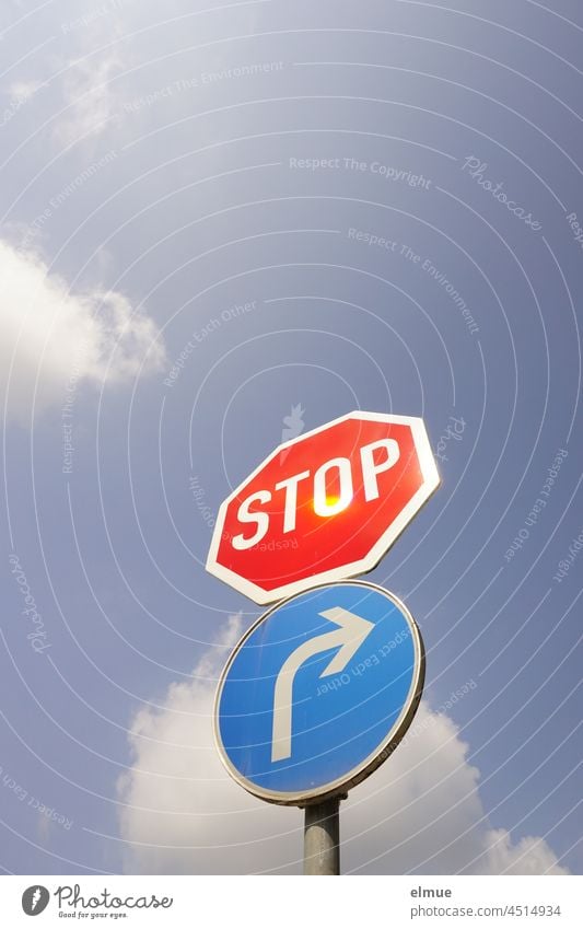 Schilder I Verkehrszeichen Stop und vorgeschriebene Fahrtrichtung nach rechts vor blauem Himmel mit Wolken aus der Froschperspektive / VZ 206 und VZ 209-20