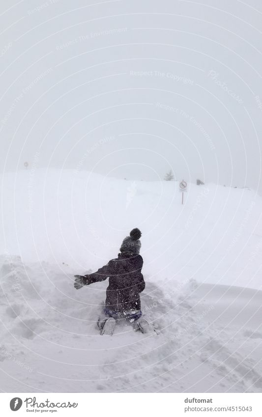 Kind spielt im Schnee auf Skipiste bei Nebel Wetter Tiefschnee Gipfel Winter Berge u. Gebirge Schneebedeckte Gipfel Alpen Landschaft kalt Spaß frieren