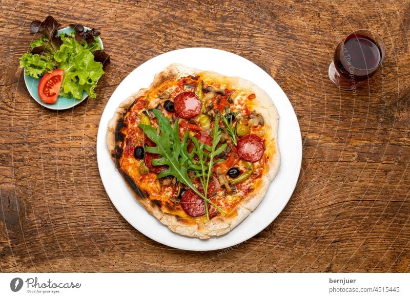 Pizza auf Holz Rotwein Aufsicht Mahlzeit Essen Abendessen Peperoni italienisch Mozzarella Käse hausgemacht Teig Scheibe heiß Tomate Sauce Wurst Italien Pizzeria