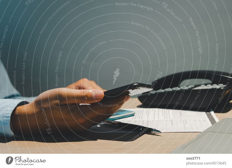 Hand hält Smartphone auf dem Schreibtisch mit Dokument Papier Arbeit und Telefon im Büro. Person Schriftstück Business Technik & Technologie Laptop Computer