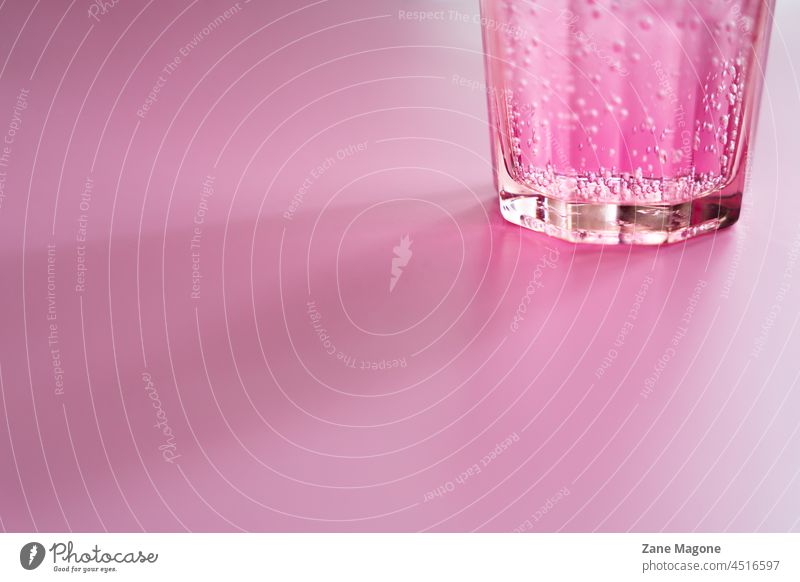Glas mit rosa kohlensäurehaltigem Getränk auf rosa Hintergrund trinken Alkohol Partygast Partygetränk Cocktail Soda Limonade funkelnd Schaumblase sprudelnd