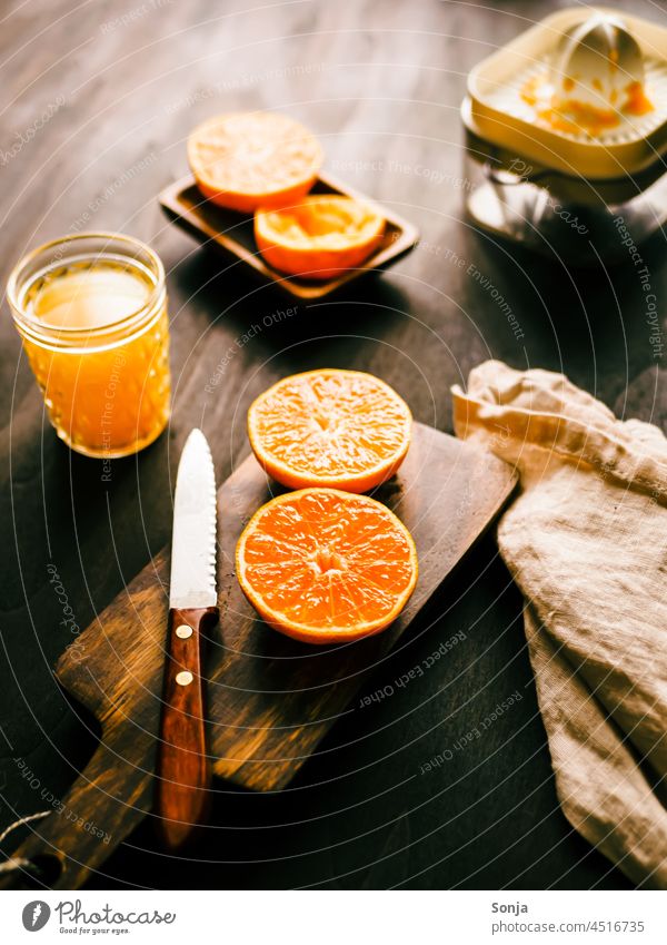 Frisch gepresster Orangensaft auf einem Holztisch in der Morgensonne orangensaft trinkglas saftpresse schneidebrett Frühstück Foodfotografie Gesundheit