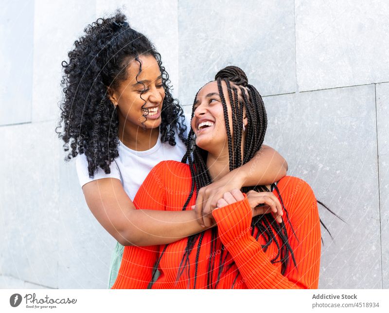 Lächelnde diverse Freunde stehen und umarmen sich auf der Straße Frauen Umarmung Umarmen Glück heiter urban positiv vielfältig rassenübergreifend multiethnisch