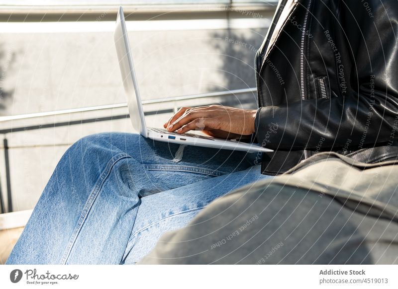 Anonyme schwarze Frau tippt auf einem Laptop Browsen Tippen Straße online freiberuflich Arbeit Notebook modern Netbook Apparatur Computer tragbar Internet