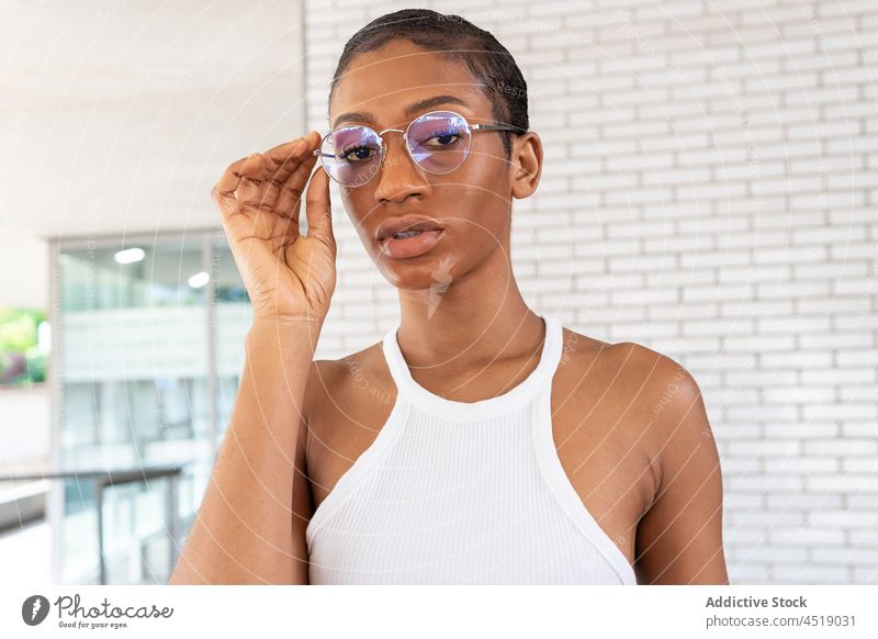 Attraktive schwarze Frau in der Nähe einer Ziegelmauer Straße Stil trendy Outfit Kleidung Backsteinwand feminin Kleidungsstück Brille Afroamerikaner Dame modern