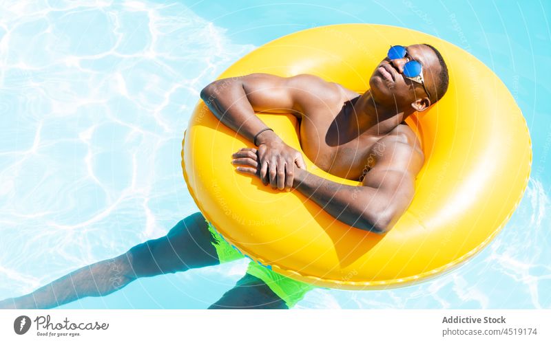 Entspannter schwarzer Mann auf aufblasbarem Ring ruhen Schwimmsport Pool sich[Akk] entspannen Sonnenbad Wasser Freizeit Sommer ohne Hemd männlich Bräune