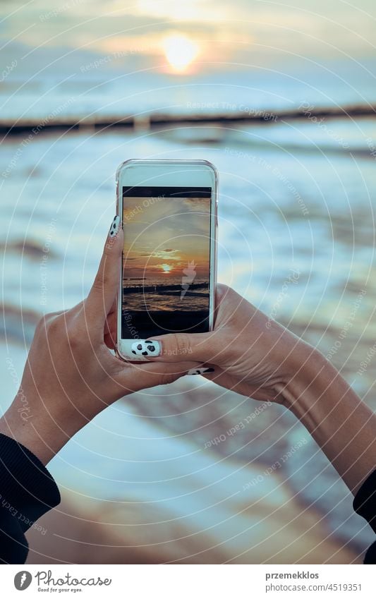 Junge Frau fotografiert den Sonnenuntergang über dem Meer mit ihrem Smartphone während einer Sommerreise Foto MEER Fotograf Bild Technik & Technologie