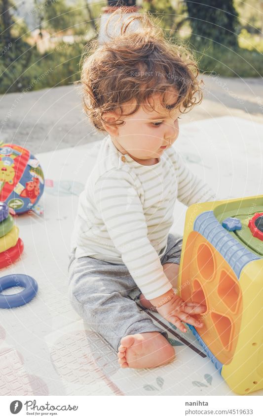 Kleines Baby genießt den Tag beim Spielen mit ihrem Spielzeug spielerisch Säuglingsalter Elternschaft Kleinkind Glück Fröhlichkeit genießen Kindergarten