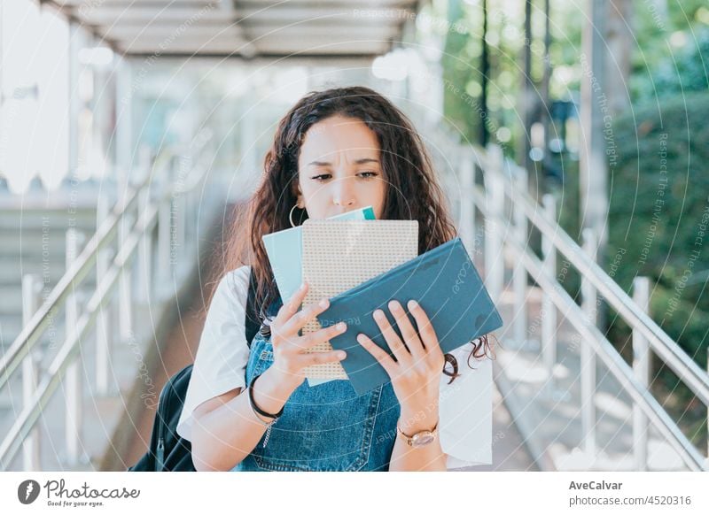 Junge Studentin, die besorgt ein Bündel Bücher hält, während sie zum Unterricht in der Universität geht, Hipster-Stil, Studienkonzept, Bücher und Tasche Bildung