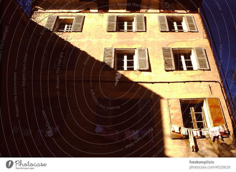 alte französische Hausfront mit viel Schatten und Sonne Kontrast und Wäscheleine am Fenster hausfront fenster Alltag leben alltagstauglich Nostalgie nostalgisch