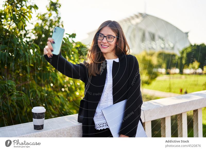 Lächelnde Frau, die auf einer Brücke ein Selfie mit ihrem Smartphone macht Arbeiter benutzend Stil positiv formal elegant Selbstportrait Geschäftsfrau Exekutive