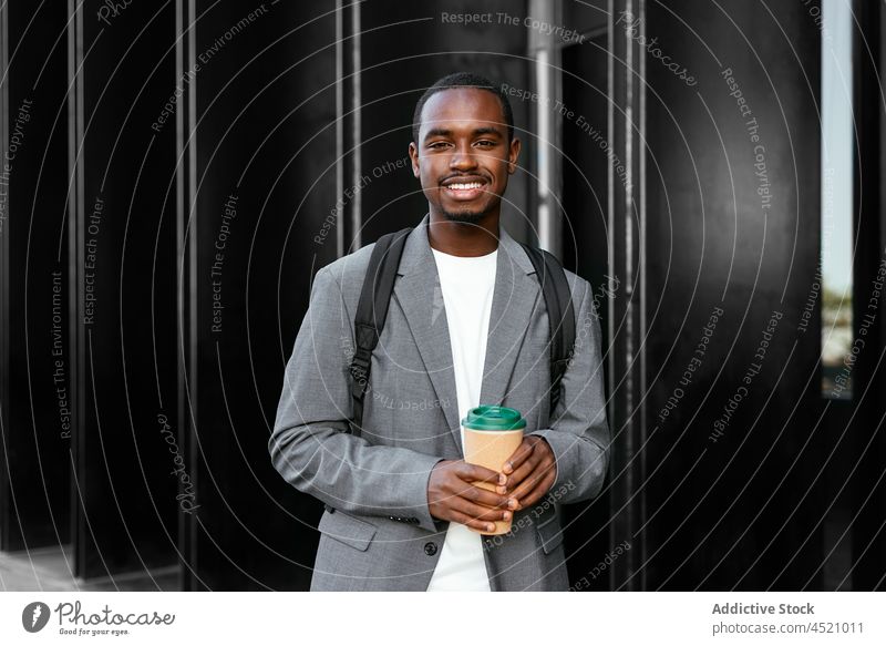 Lächelnder schwarzer Mann mit Kaffee zum Mitnehmen Exekutive Einwegartikel Imbissbude positiv formal Stil gut gekleidet Vorschein männlich Zahnfarbenes Lächeln
