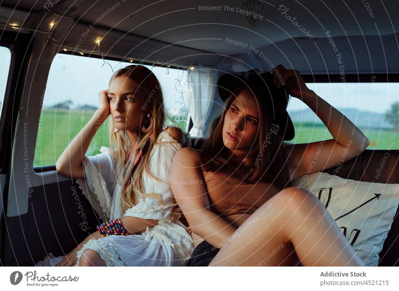 Zwei schöne kaukasische Mädchen in Sommerkleidung liegen auf dem Sitz in einem Oldtimer-Van und schauen weg zwei hübsch niedlich Frau jung brünett blond