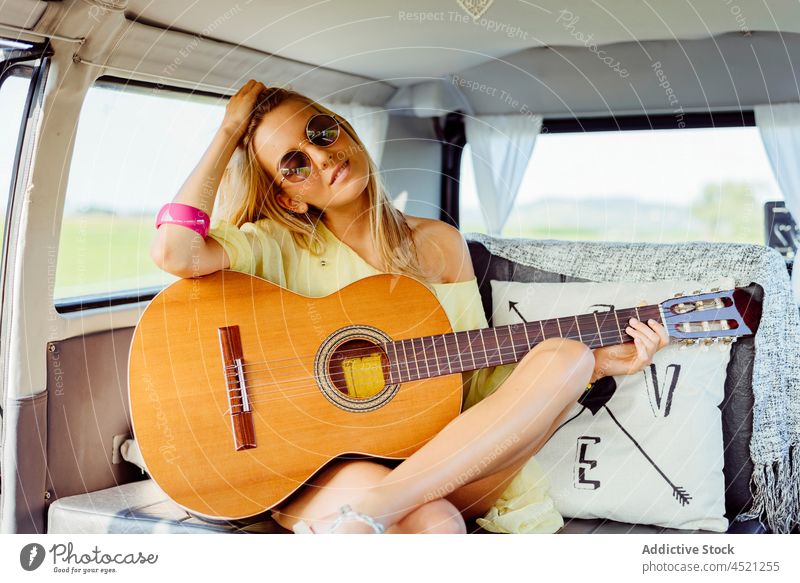 Schönes blondes Mädchen in Sommerkleidung spielt Gitarre hübsch niedlich jung Frau Kaukasier Spielen Musik Glück Freizeit Sonnenbrille Sitzen Kleintransporter