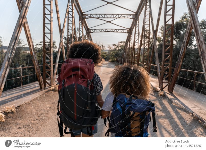 Schwarze Frauen mit Rucksäcken gehen auf einer alten Brücke Reisender Abenteuer Wanderung Natur erkunden genießen Wald Aktivität Zusammensein Freundschaft
