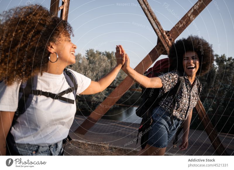 Fröhliche schwarze Frauen geben High Five auf der Brücke Wanderer high five Lachen Glück Spaß Freundschaft Abenteuer bester Freund Freundin sorgenfrei Wanderung