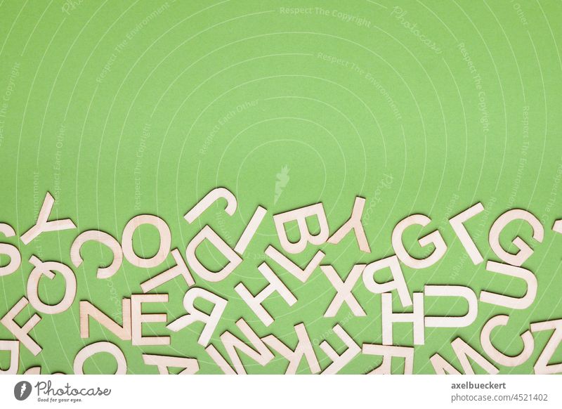 Durcheinander aus Holzbuchstaben auf grünem Papierhintergrund Buchstaben durcheinander Flat lay Hintergrund hölzern Design Farbe abstrakt Großbuchstaben