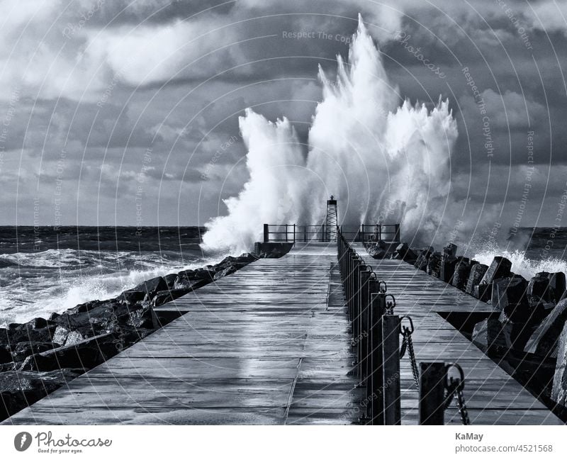 Schwarzweiß Aufnahme des Leuchtturms auf der Mole von Nørre Vorupør bei Sturm und hohen Wellen, Jütland, Dänemark Wetter Orkan Pier Küste Seegang Meer Ozean