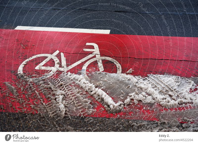 Radweg mit roter Fahrbahnmarkierung bei winterlichen Straßenverhältnissen. straße fahrradweg fahrbahnmarkierung richtung asphalt wegweiser hinweis Schneematsch