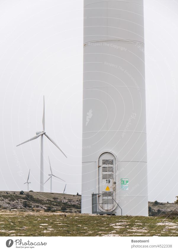 Windpark in den Bergen. Turm einer Windkraftanlage mit Tür zum Aufstieg. Im Hintergrund weitere Anlagen. 19 Gebirge Energie Erneuerbare Energie