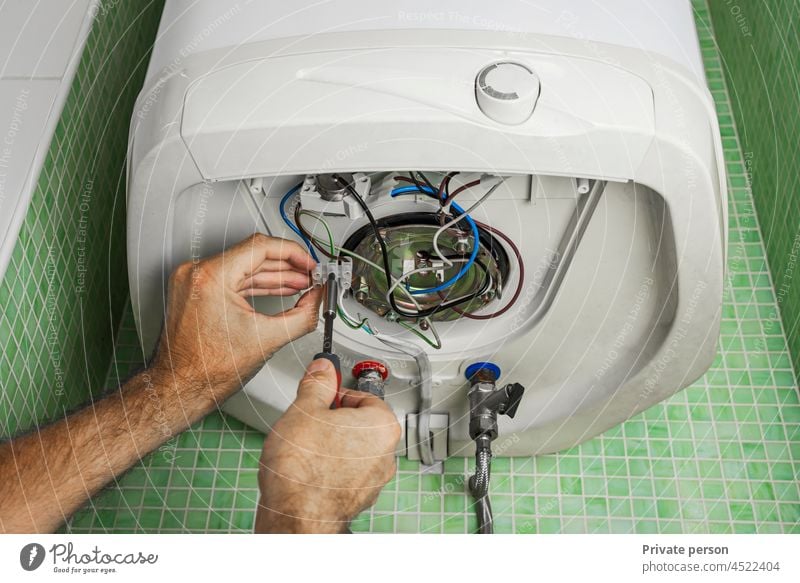 Reparatur eines Warmwasserbereiters oder Boilers, mit elektrischen Leitungen und Rohren im Badezimmer, Nahaufnahme. Heizkessel Elektromonteur Stromanschluss