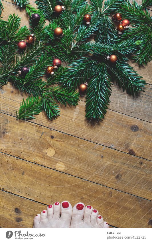 grünes tannenzeugs mit weihnachtskugeln auf holzboden und rotlackierten fußzehen weinachtlich Tannenzweige Tradition Weihnachten & Advent Weihnachtsdekoration