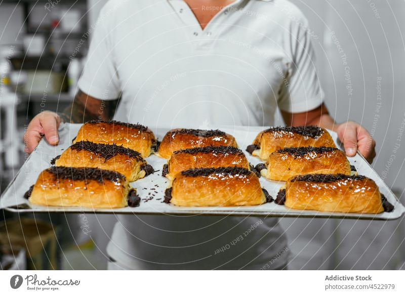 Bäcker zeigt frisch gebackenen Kuchen mit Schokolade Mann Dessert Küchenchef süß Koch lecker bestäuben männlich geschmackvoll appetitlich kulinarisch Sahne