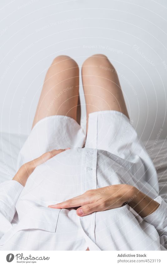 Anonyme schwangere Frau mit Hand auf dem Bauch auf dem Bett liegend Angebot sanft mütterlich Harmonie positiv vorwegnehmen erwarten Schwangerschaft sorgenfrei